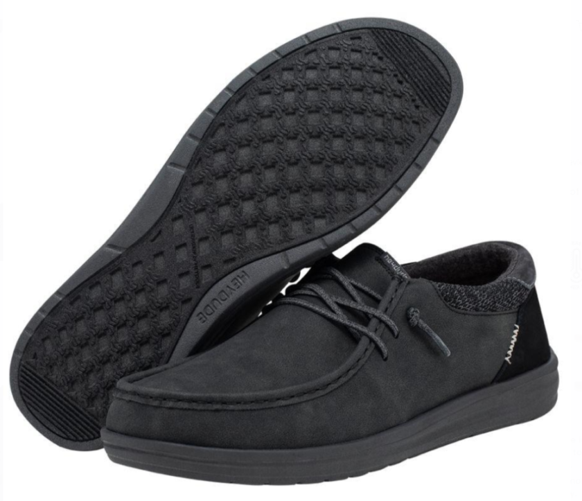 "Pair of Heydude 112294938 men's shoes in all-black color, featuring moc toe stitching, flexible laces, textured knit collar, and a waffle-patterned rubber outsole."
