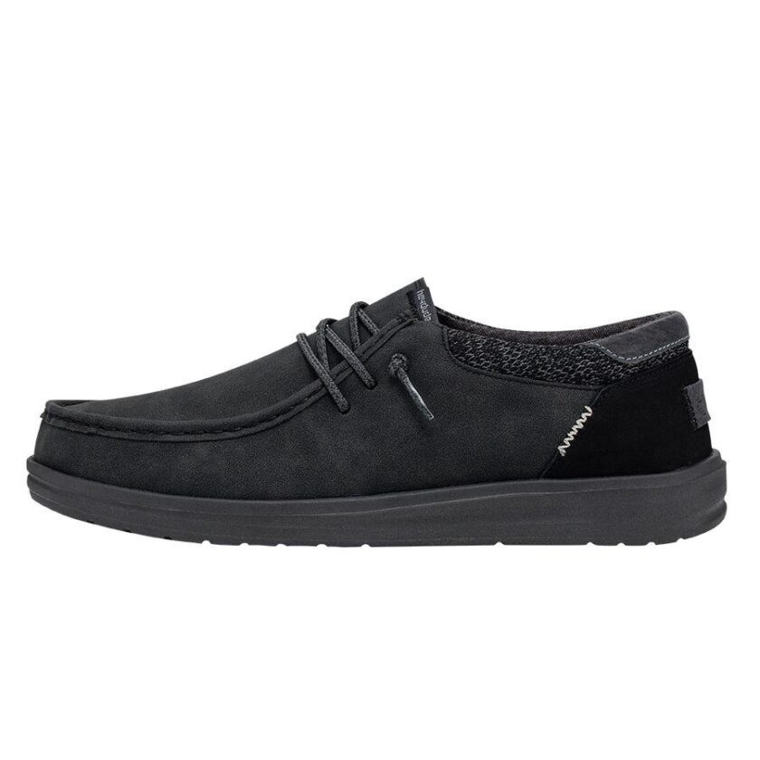 "Side view of Heydude 112294938 men's shoe in solid black, featuring a moc toe design, black laces, and textured ankle panel."