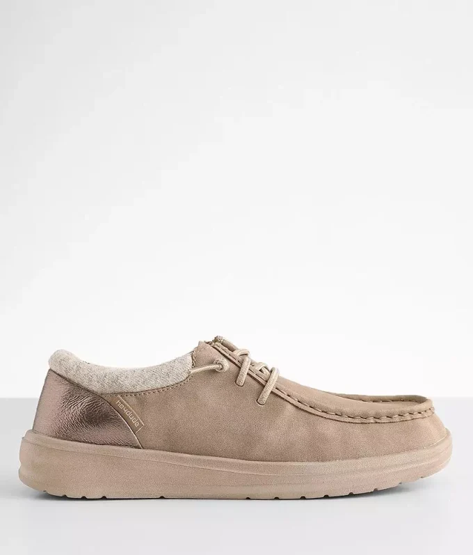 "Side view of HEYDUDE shoes model 121883707 in taupe with metallic bronze heel accent, beige cushioned sole, and soft knit collar, displayed on a light gray surface."