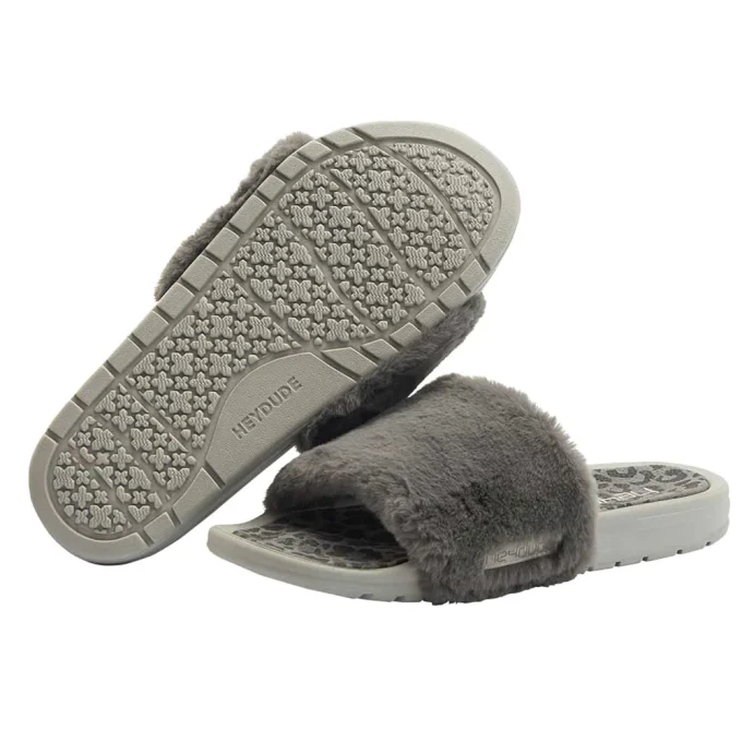 "A pair of gray HEYDUDE slide sandals featuring plush faux fur straps and textured rubber soles for comfort and grip."