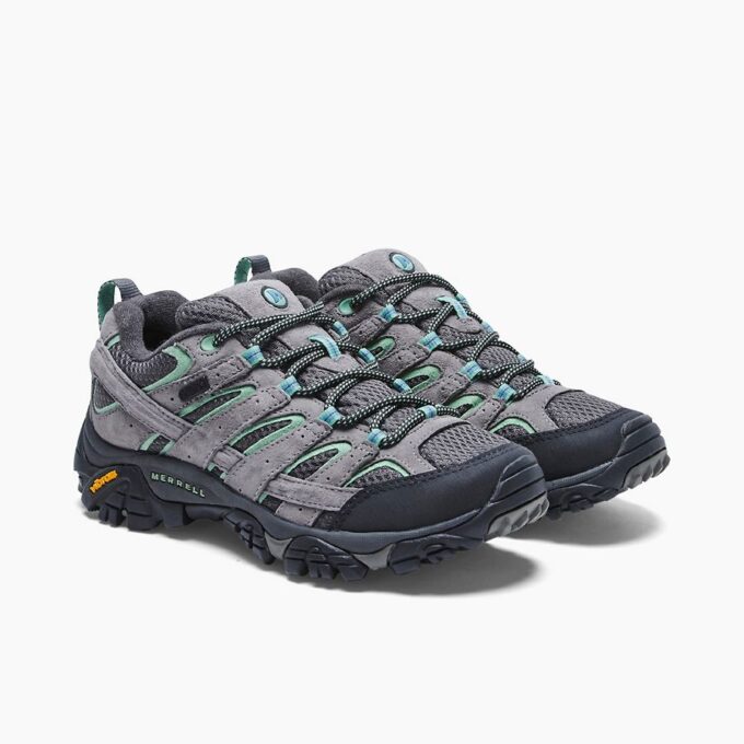 "Angled side view of the Merrell J06028 hiking shoes in grey with teal and black accents, featuring durable suede and mesh uppers, Vibram® rubber outsoles, and signature Merrell branding near the heel."