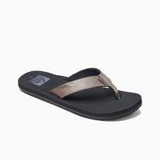 "Angled view of Reef RF002915GRE sandal showcasing a brown leather strap, black cushioned footbed, and the Reef logo printed near the heel."
