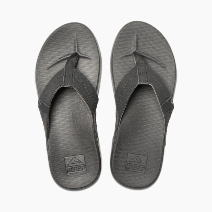 "Top view of Reef RF0A3FDIBLA men's black flip-flop sandals featuring textured footbeds, wide synthetic leather straps, and embossed Reef logo on the heel."
