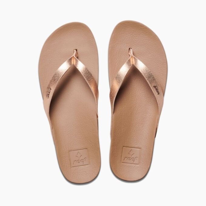 "Top-down view of Reef RF0A3FDSRGL women's flip-flops featuring tan textured footbeds and metallic rose gold straps with embossed Reef branding near the toes."