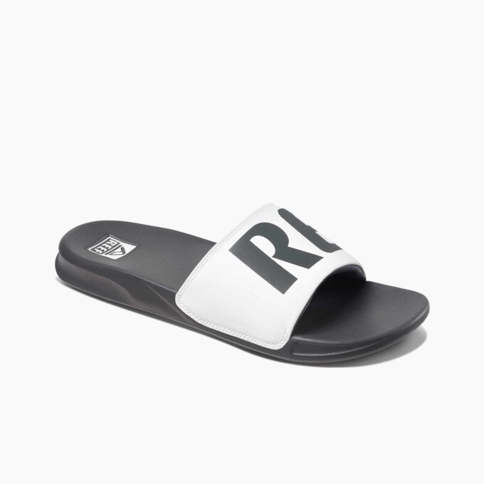 "Angled view of the Reef RF0A3ONDGRW slide sandal featuring a black contoured footbed and a wide white strap with bold black 'REEF' branding."