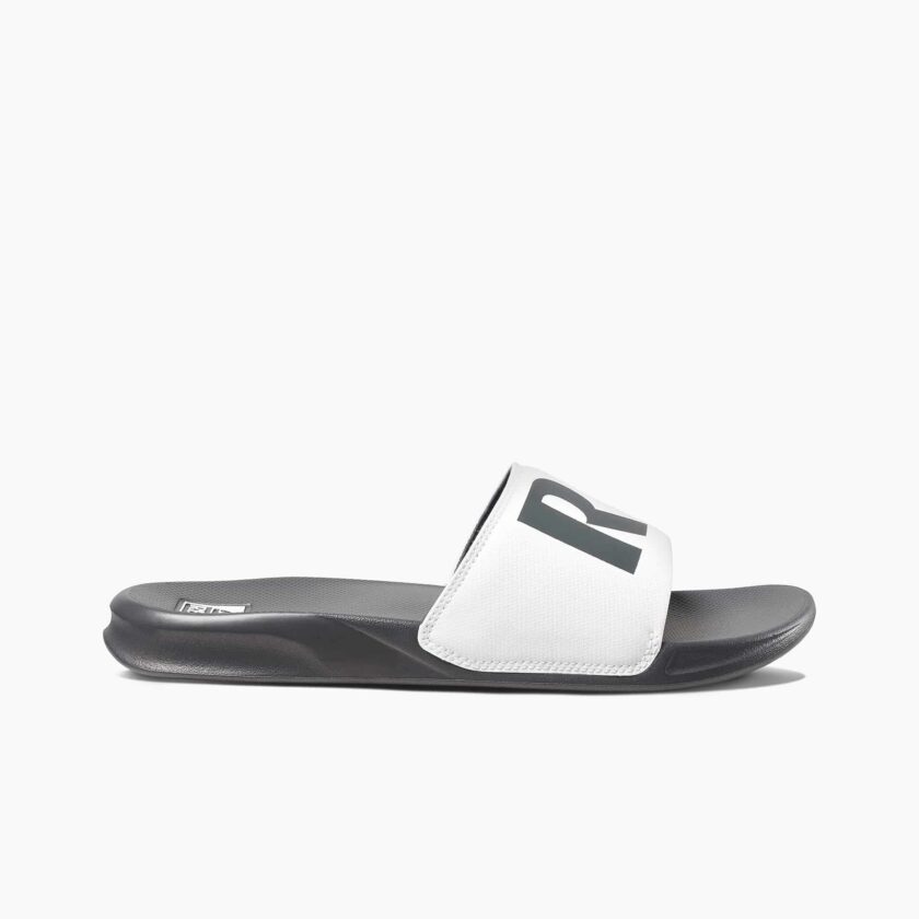 "Side view of the Reef RF0A3ONDGRW slide sandal featuring a black contoured footbed and a white strap with bold black lettering."