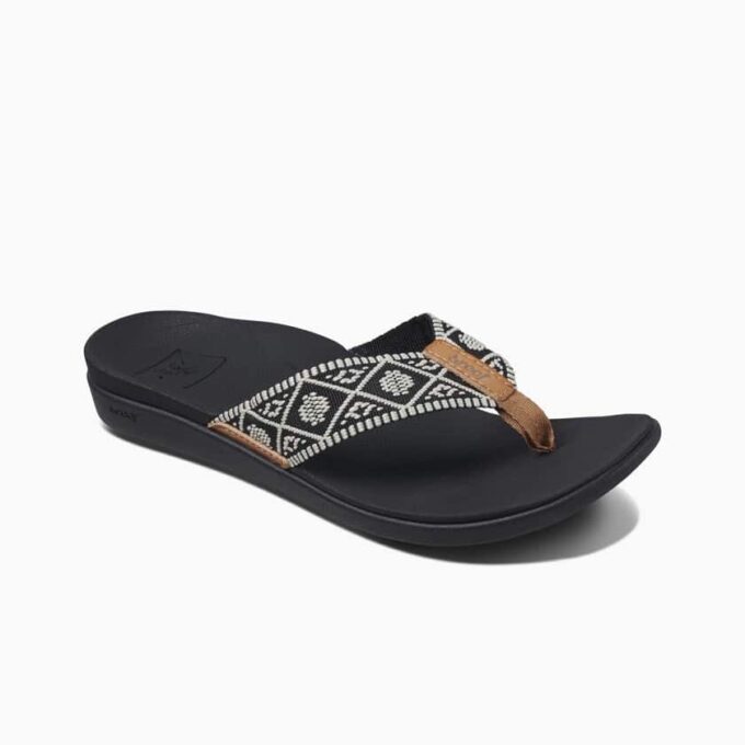 “Side view of a Reef RF0A3VDNBLW sandal featuring a black sole and a black-and-white patterned fabric strap with brown accents and the Reef logo.”