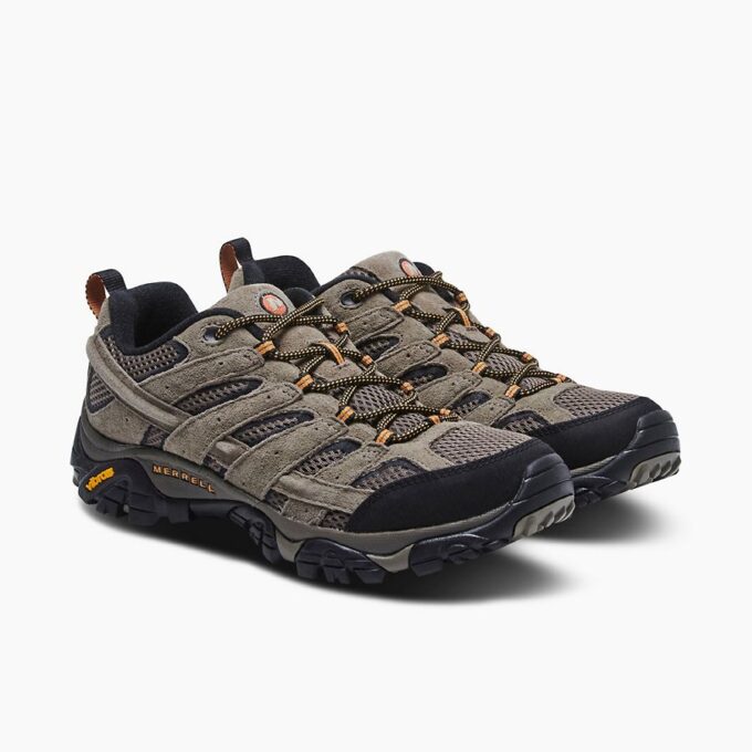 "Pair of Merrell J06025 hiking shoes shown from a front-side angle, featuring gray suede and mesh uppers, black and orange accents, rugged black soles with Vibram branding, and black-and-yellow laces."
