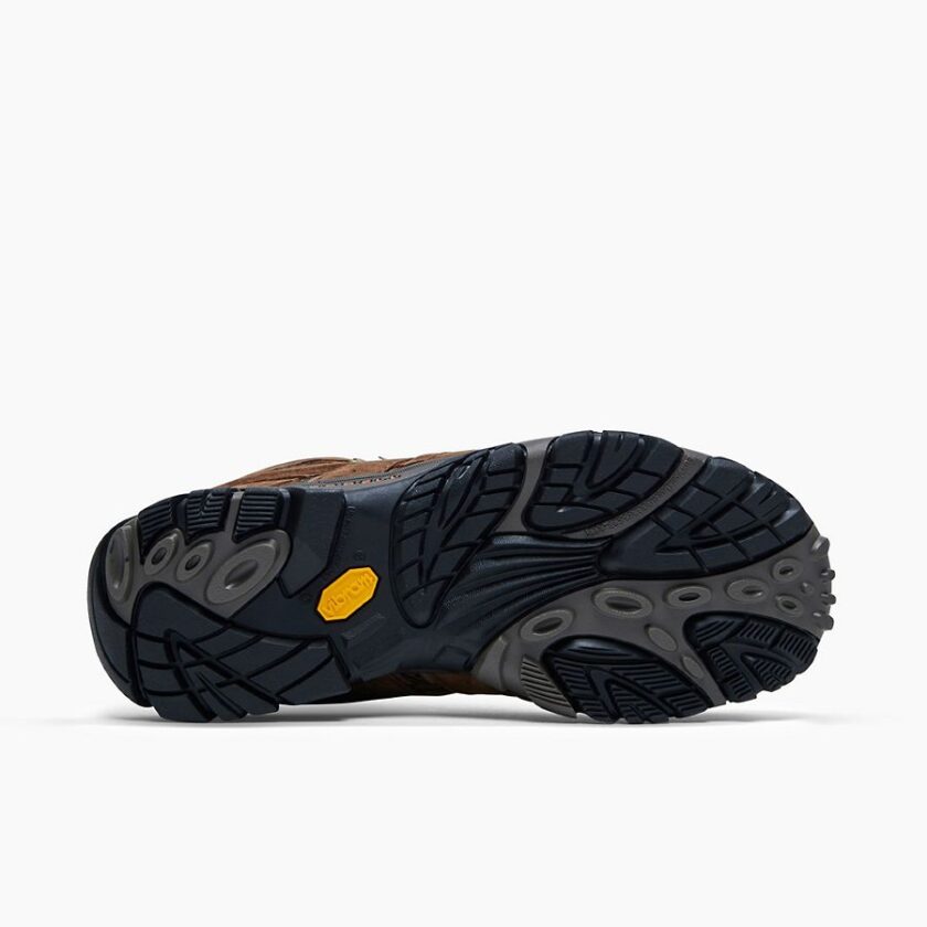 "Close-up view of the black and grey Vibram outsole of a brown Merrell J06051 hiking boot, showing its detailed tread pattern and yellow Vibram logo."