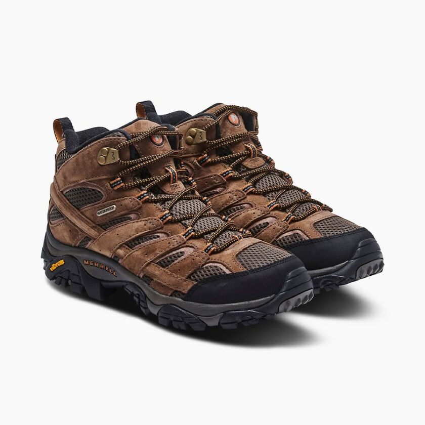 "Pair of brown Merrell J06051 hiking boots with black toe caps, mesh panels, and orange-accented laces, positioned side-by-side at a slight angle, showing the outer sides and soles with Vibram branding."