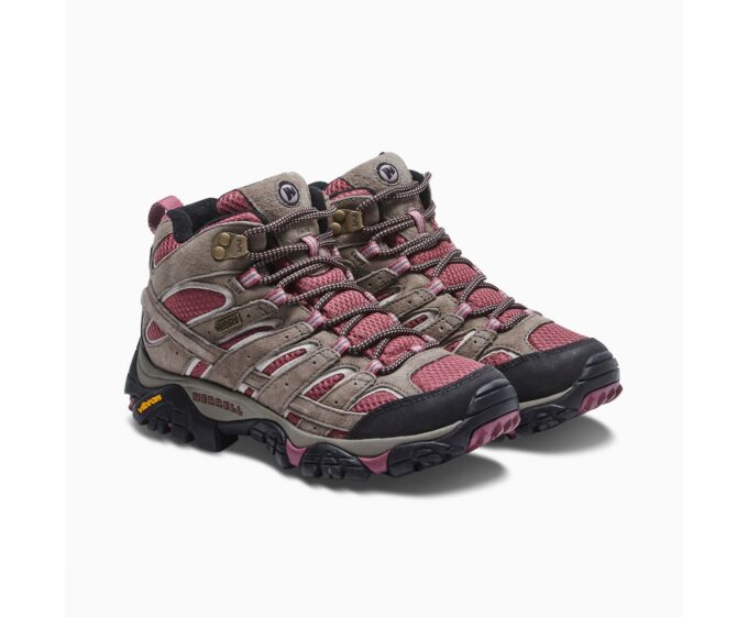 "Side view of a pair of Merrell J06052 hiking boots in brown suede and burgundy mesh, featuring black and pink patterned laces, black rubber toe caps, and black Vibram outsoles with burgundy accents, displayed against a white background."
