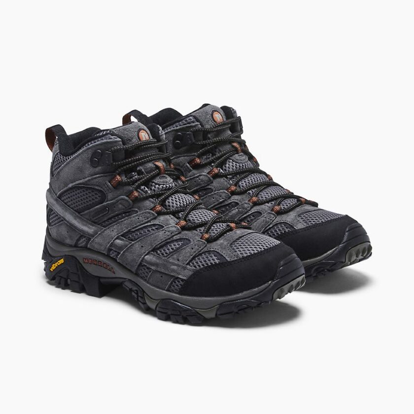 "Pair of Merrell J06053 hiking shoes in dark gray with black and orange accents, shown from a front-side angle on a white background. The shoes feature mesh and suede uppers, black toe caps, black and orange laces, and Vibram soles."