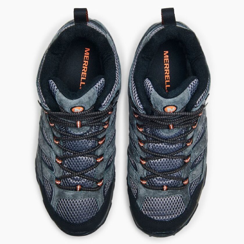 "Top view of a pair of Merrell J06053 hiking shoes in dark gray with black and orange accents. The shoes feature black and orange laces, mesh and suede uppers, and the "Merrell" logo printed in orange on the insoles."