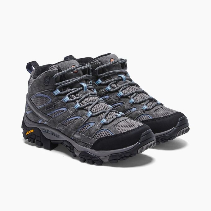 "Side view of a pair of Merrell J06054 hiking boots in gray and black with blue accents, featuring mesh and suede upper, detailed lacing system, Vibram sole, and waterproof label on the side."