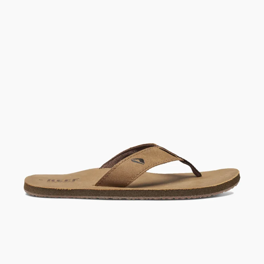 "Side view of brown Reef RF000232BZB flip-flop sandal with cushioned footbed and suede strap featuring a small logo."