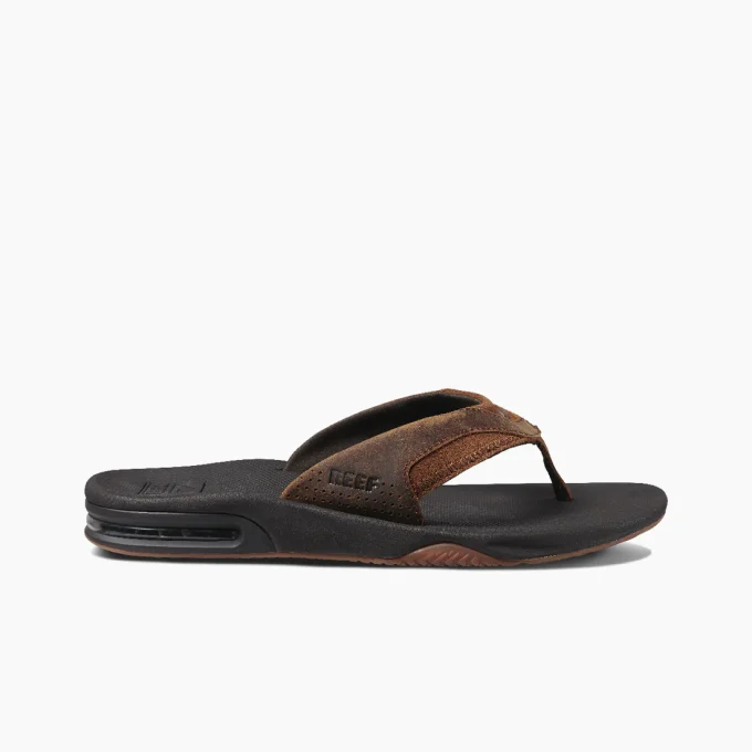 “Side view of a Reef RF002156BRZ sandal featuring brown suede straps, a black cushioned footbed, and a visible air-cushion sole for added comfort.”