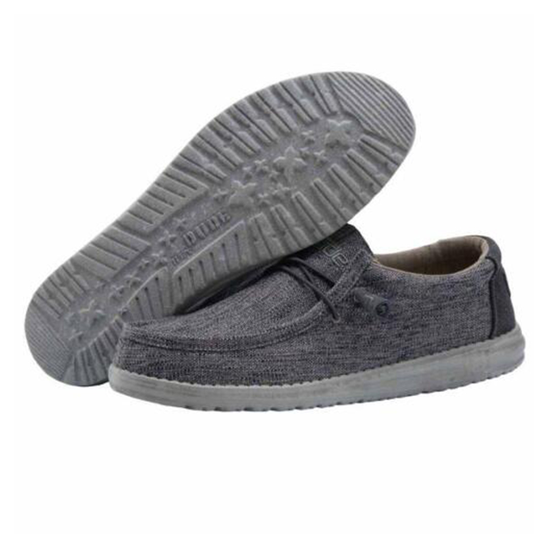 "Pair of Heydude Wally Woven Carbone casual shoes in dark grey woven fabric with a lightweight grey rubber sole, featuring elastic laces and slip-on design for men, shown from side and bottom views."