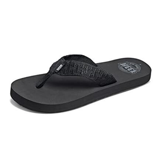“Black Reef Smoothy flip-flop sandal with a textured fabric thong strap and a cushioned sole featuring the Reef logo.”