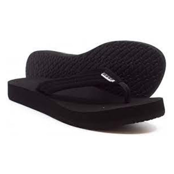 "Angled view of Reef Cushion women's sandals (model RF001454BK2) in black, showcasing textured rubber outsoles for grip, cushioned footbeds, and soft fabric thong straps with a small Reef logo tag."